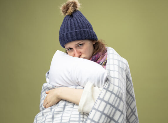 女人悲伤的生病的年轻女孩穿着白色长袍 戴着冬天的帽子 围巾裹着格子呢抱枕长袍冬天包裹