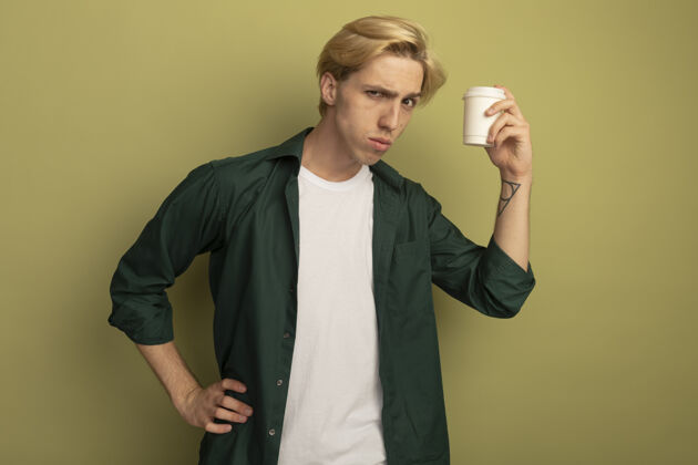 手一个穿着绿色t恤 手放在臀部 手里拿着一杯咖啡的年轻金发男人人男人手