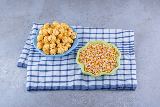 配料在大理石表面的毛巾上放上几碗玉米粒和涂了焦糖的爆米花零食垃圾食品玉米