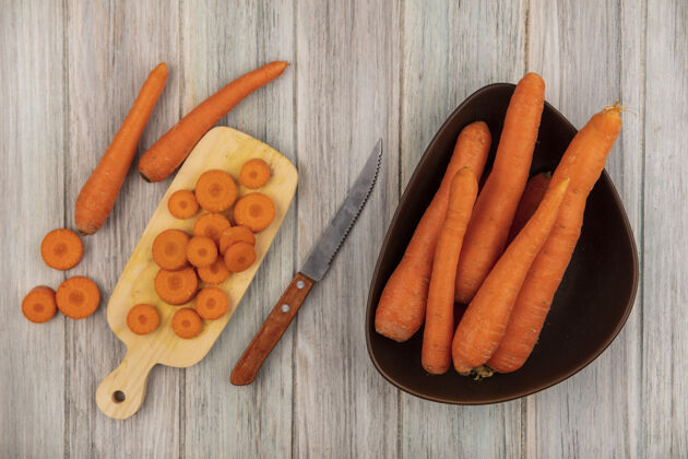 剁碎顶视图美味切碎的胡萝卜在一个木制的厨房板与刀胡萝卜在一个灰色的木制背景碗胡萝卜视图美味
