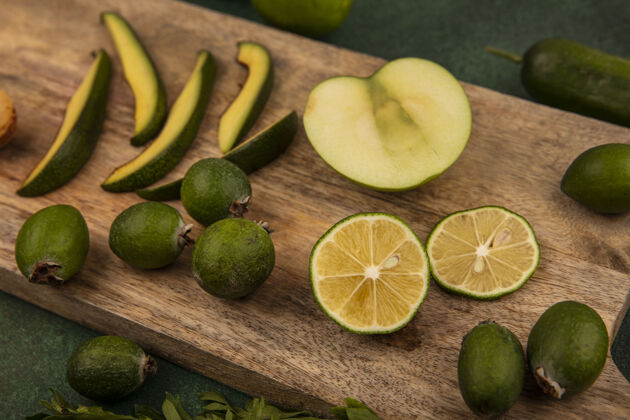 膳食健康食品的俯视图 如鳄梨片 半青柠和苹果 在绿色背景的木制厨房板上隔离开来鳄梨健康顶部