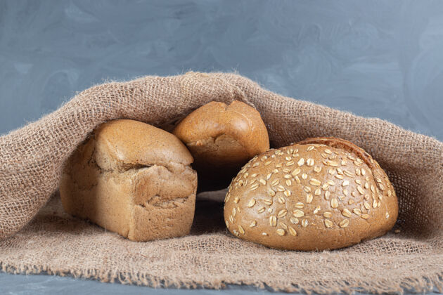 美味三个面包包在大理石表面的织物盖下美味面包皮美味