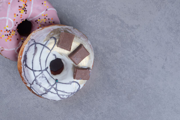 糕点两个美味的甜甜圈捆在一起放在大理石表面釉面顶部甜点