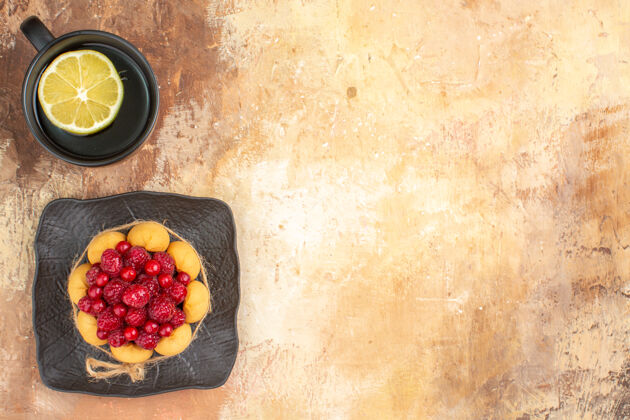 浆果一个带有覆盆子的礼品蛋糕和一杯放在棕色托盘上的柠檬茶的水平视图营养膳食胡椒