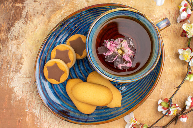 食物上图各种饼干一杯茶和鲜花放在五颜六色的桌子上香薰茶碗
