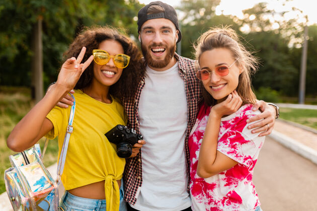 女人快乐的年轻朋友们带着相机在公园里散步 男女一起玩得很开心年轻多种族微笑