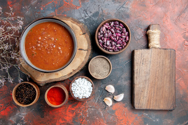 圆形头顶上的经典番茄汤上的木托盘豆不同的香料和棕色的切割板上的混合色桌混合豆子香料