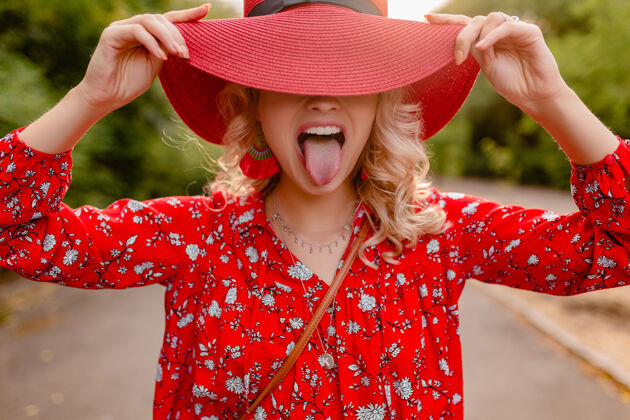 舌头迷人的时尚金发微笑的女人在稻草红帽子和衬衫夏季时尚装搞笑明亮女人脸
