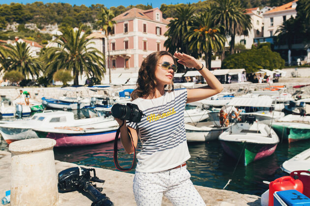 阳光迷人的女人在欧洲海边度假 在游轮上用相机拍照假期美丽年轻