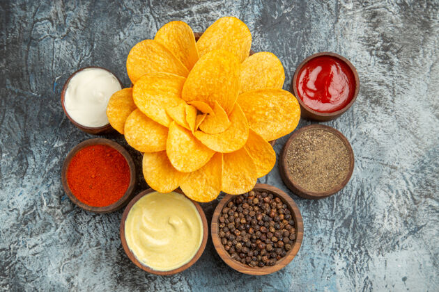 薯片上图：灰色桌子上 自制的薯片装饰得像花朵形状的蛋黄酱和番茄酱新鲜番茄酱食物