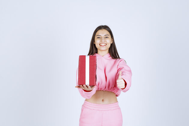 促销穿着粉色睡衣的女孩手里拿着一个红色长方形礼盒 看上去很满意人工人聪明