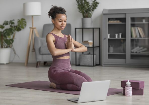 瑜伽健身女士在家里用瑜伽垫做瑜伽人体电脑企业
