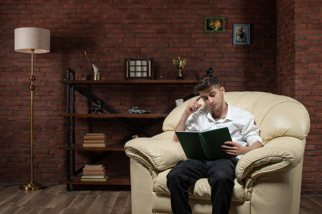 扶手椅男青年坐在沙发上看书房内工作晚上工作房的正面图晚上键盘乐器年轻男性