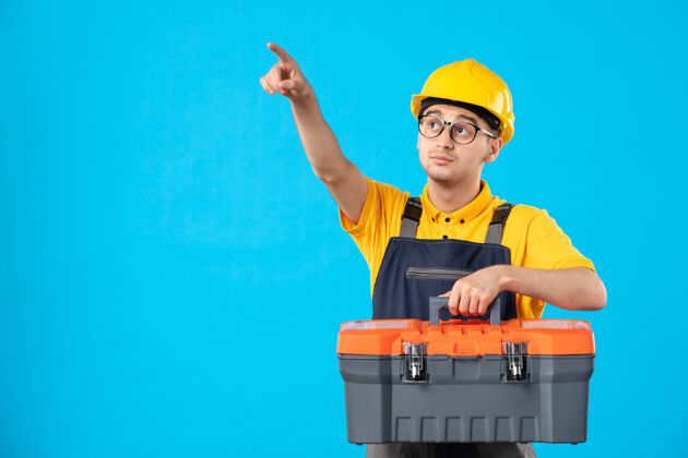 男工人身穿黄色制服的男性工人正面图 蓝色工具箱指向上方勾缝工制服表面工