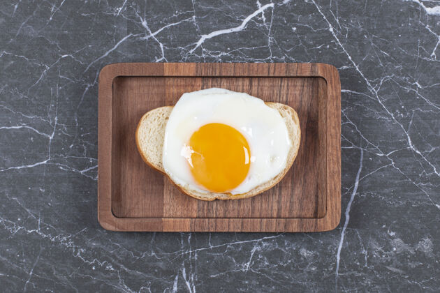 可口把煎鸡蛋放在面包上 切成薄片放在木板上 放在大理石表面板子面包煎蛋