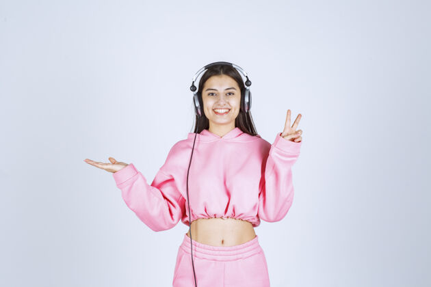 模特穿着粉色睡衣的女孩戴着耳机 展示着享受的标志高质量的照片人体模特人人类