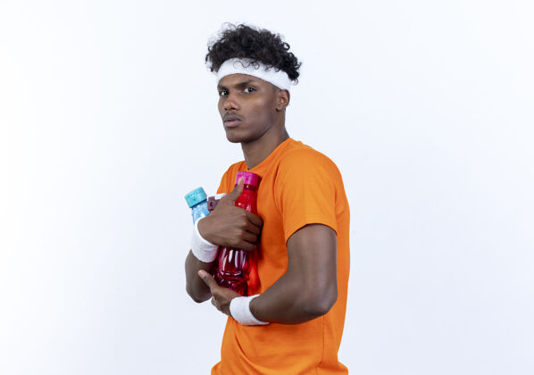 瓶子年轻的美国黑人运动男子戴着头带和手环拿着水瓶年轻的腕带抱着