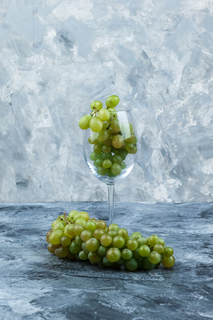 秋天在深蓝色和浅蓝色大理石背景上放上一杯白葡萄 特写葡萄酒果汁葡萄