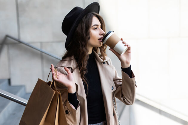 音乐购物日咖啡休息时间穿着纸袋走在城市街道上的迷人的年轻女子成人女人女性