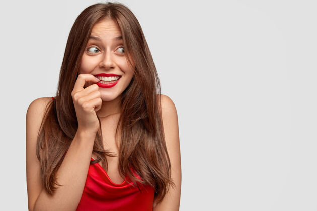 牙齿积极的欧洲女人带着神秘的快乐表情 把食指放在嘴边口红积极梦幻