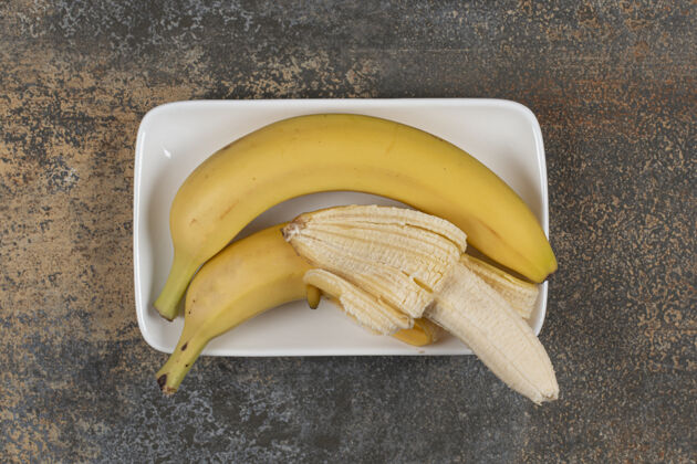 香蕉把去皮和不去皮的香蕉放在白色盘子里热带零食有机
