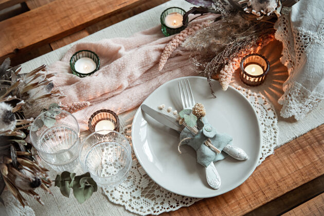 节日婚礼或情人节的浪漫餐桌 点燃蜡烛和干花优雅布料摆设