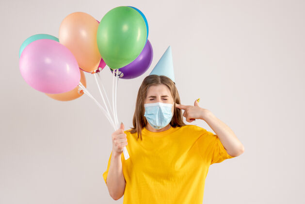 面具年轻的女性手持彩色气球 戴着白色的无菌口罩年轻女性观看消毒