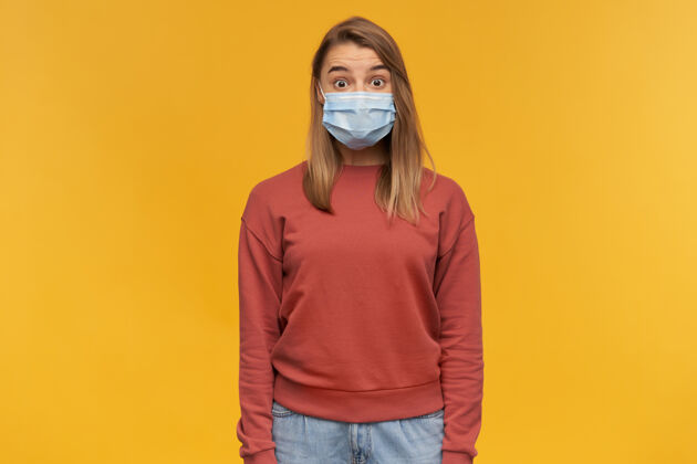 病毒震惊的年轻女子戴着防病毒面具站在黄色的墙上 脸上贴着防冠状病毒面具非凡成人