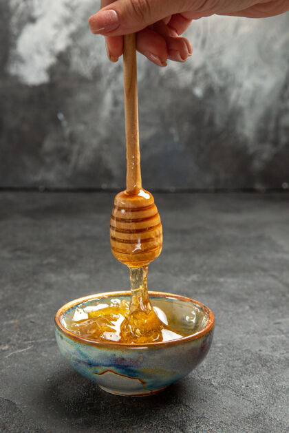 甜味剂前视图甜甜的蜂蜜在黑暗的盘面上甜甜的蜂蜜甜甜的蜜蜂酒高脚杯杯子