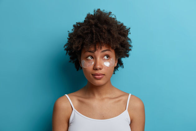 年轻化年轻的黑皮肤非洲头发的女人在眼睛下面涂上水凝胶银片 减少浮肿 去除黑眼圈护肤理念年龄模特皱纹
