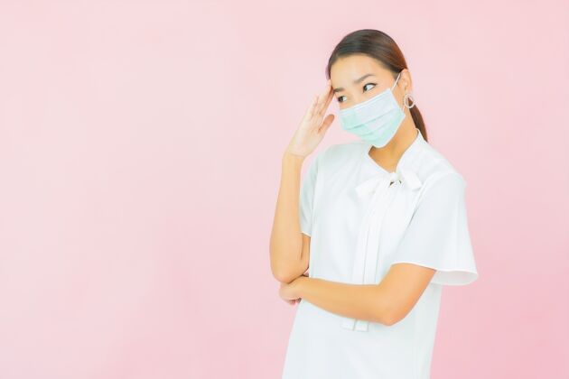 预防肖像美丽的亚洲年轻女子戴着面具在粉红色的墙上保护covid19疾病药阳性