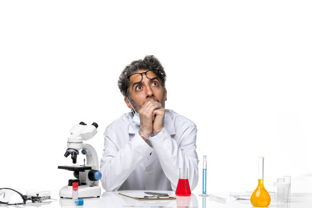 思维正面图中年科学家穿着特制的白色西装围坐在桌子旁思考解决方案科学医学专业