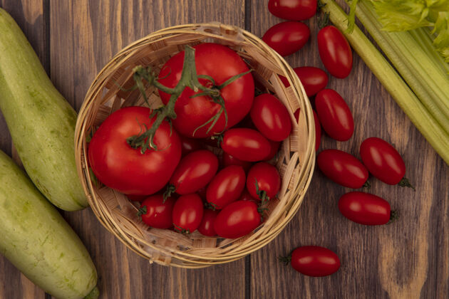 番茄桶上有机红色西红柿的俯视图 木墙上隔离着西葫芦和芹菜食品顶部有机