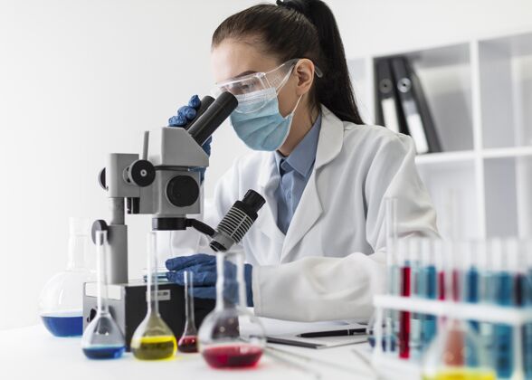 显微镜中镜头女人透过显微镜看风险化学品面罩