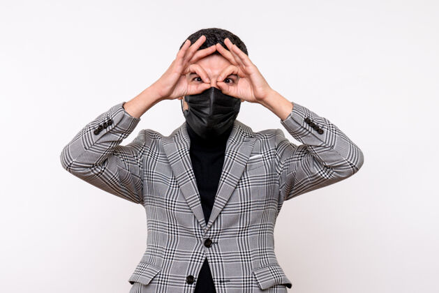 前面正面图：戴着黑色面具的年轻人站在白色孤立的背景上 把奥基标志放在眼前眼睛套装视图