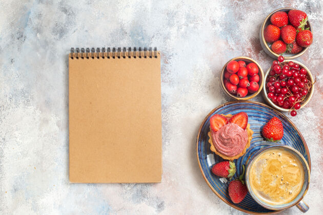 笔记本俯瞰一杯咖啡 上面放着奶油蛋糕和水果 桌上放着甜甜的饼干蛋糕棕色咖啡杯葡萄酒