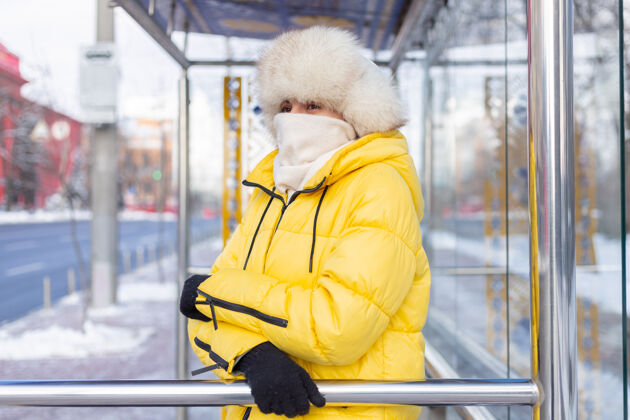 换乘在寒冷的日子里 一个穿着冬衣的女人在公共汽车站等公共汽车公共公共汽车等待