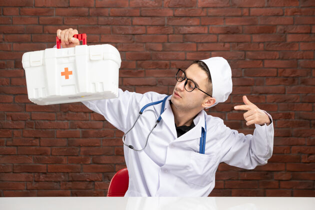 药品前视图身穿白色医疗服的年轻医生带着急救箱套装医疗工具箱