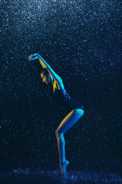 广告年轻的女芭蕾舞演员在水滴和浪花下表演白种人模特在霓虹灯下跳舞迷人的女人运动蓝色黑暗