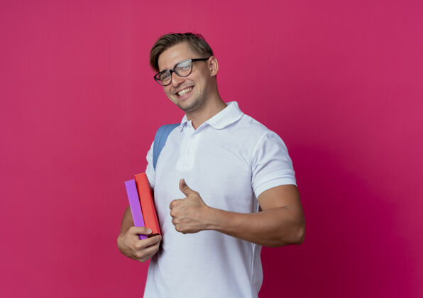拇指面带微笑的年轻帅气男生背着书包戴着眼镜拿着书年轻背部男性