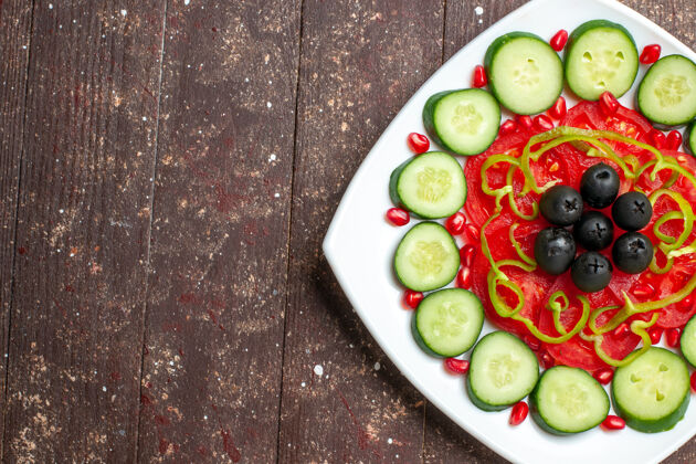 生的顶视图切片黄瓜和橄榄在一个棕色的乡村办公桌上盘子里饮食沙拉蔬菜维生素健康午餐顶部风景