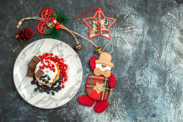 马赛克顶视图美味的奶油蛋糕葡萄干和圣诞玩具在浅黑色的背景玩具圣诞节邮资