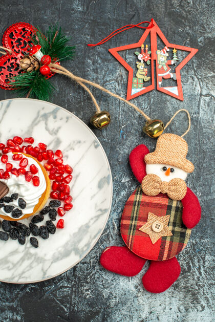 糖顶视图美味的奶油蛋糕葡萄干和圣诞玩具在浅黑色的背景饼干盘子传统