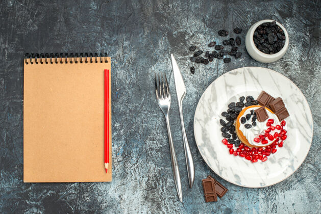 纸顶视图美味的奶油蛋糕与巧克力和葡萄干在一个浅黑色的背景糖书签葡萄干