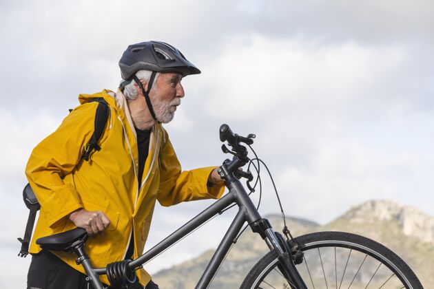 活动山上骑自行车的老人画像山头盔男性
