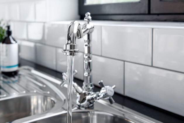 钢水槽新的和现代的钢水龙头在厨房里水槽流卫生