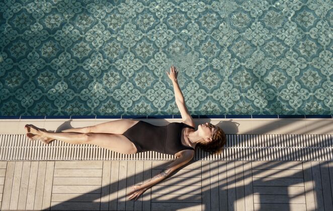 流行病一个躺在游泳池边的全副武装的女人旅游度假旅游