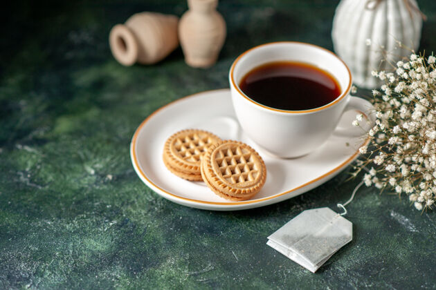 浓缩咖啡前视一杯茶 配上小甜饼 放在白色盘子里 在深色的表面上摆上彩色的早餐面包杯 喝点糖仪式糖咖啡