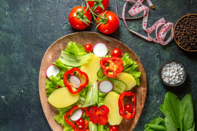 食物俯视图新鲜去皮切土豆与红辣椒萝卜绿色西红柿在一个棕色的盘子和米香料在绿黑色混合颜色的表面西红柿新鲜头顶