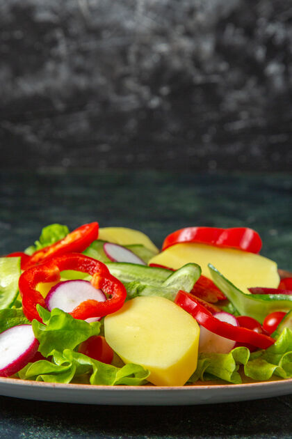 蔬菜新鲜去皮切土豆和红椒萝卜的垂直视图绿色西红柿放在一个棕色盘子里 绿黑色混合色背景番茄饮食胡椒